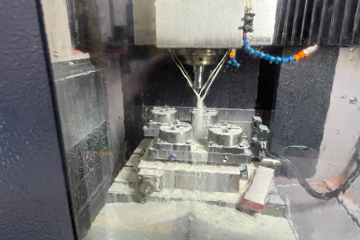 Close-up of a Makino slow-feed wire EDM head cutting a hardened S136 steel mold insert submerged in dielectric water