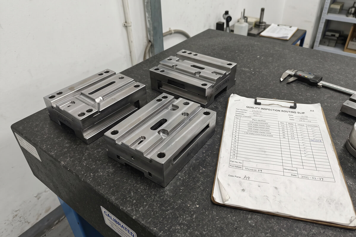 Mirror-finished S136 steel injection mold slider and cavity inserts resting on a black granite inspection surface plate