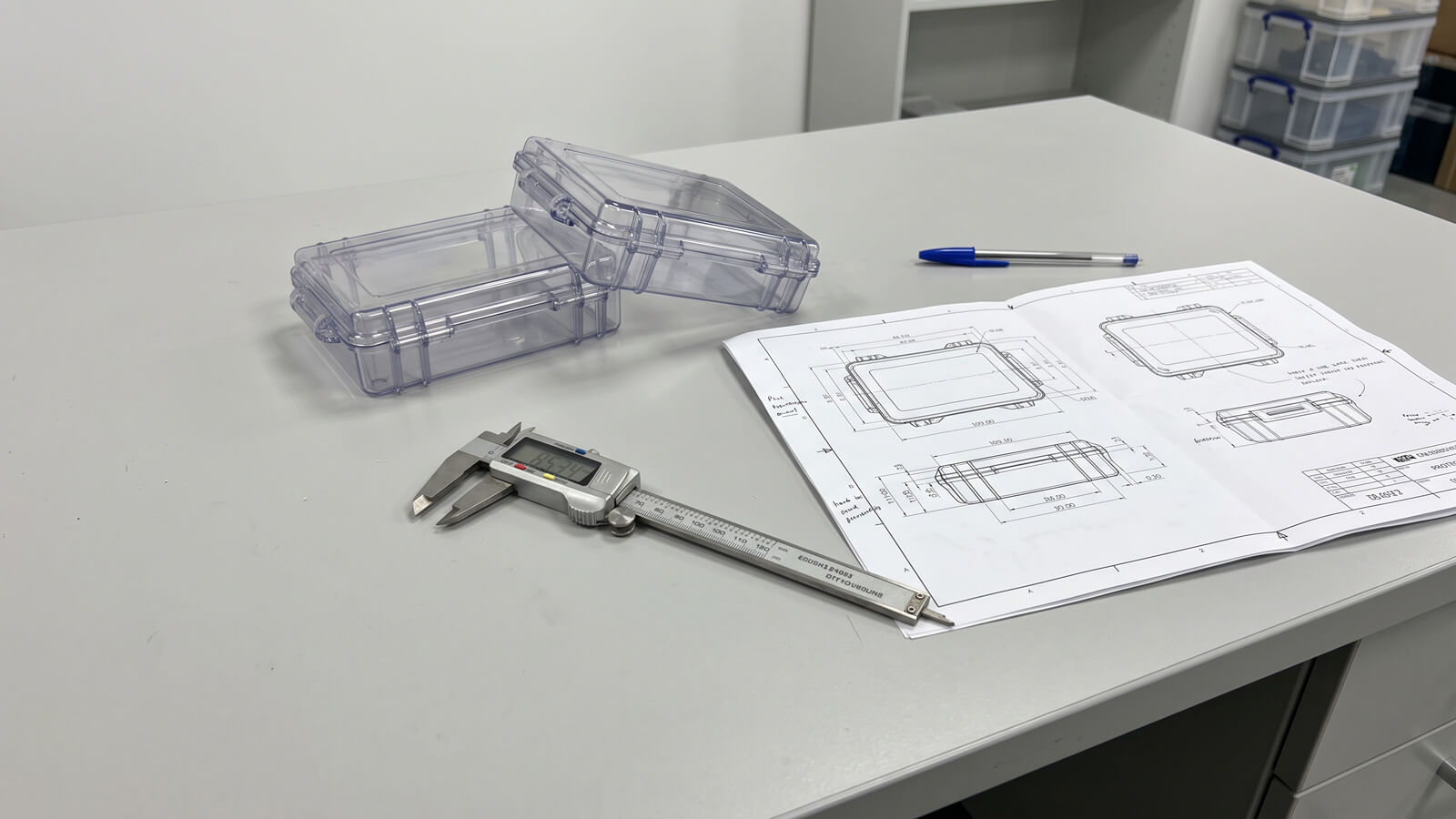 Injection molded plastic accessory samples, steel mold inserts, and digital calipers on an engineering evaluation desk