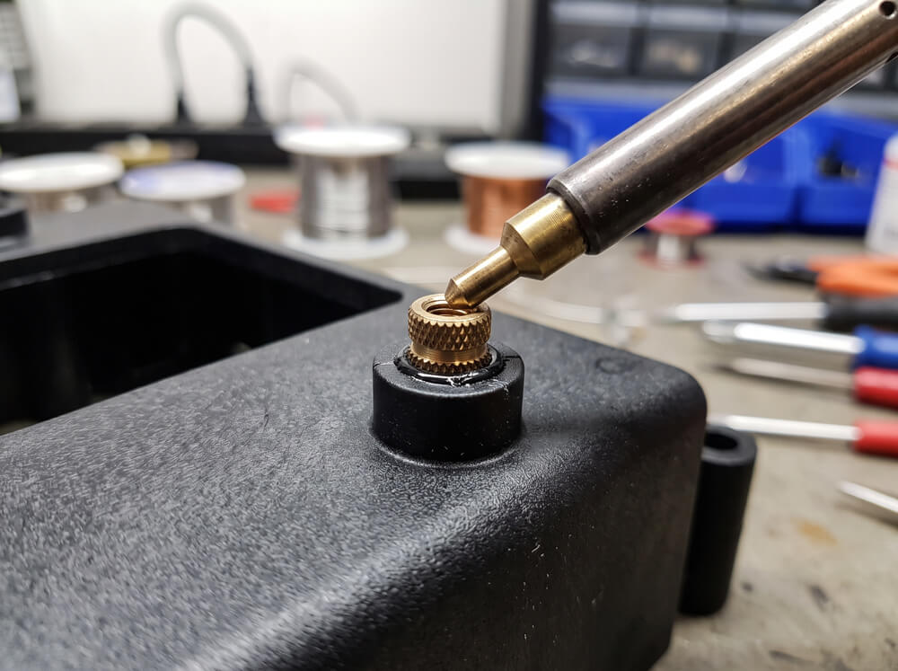 Brass threaded insert being heat-installed into a molded plastic part