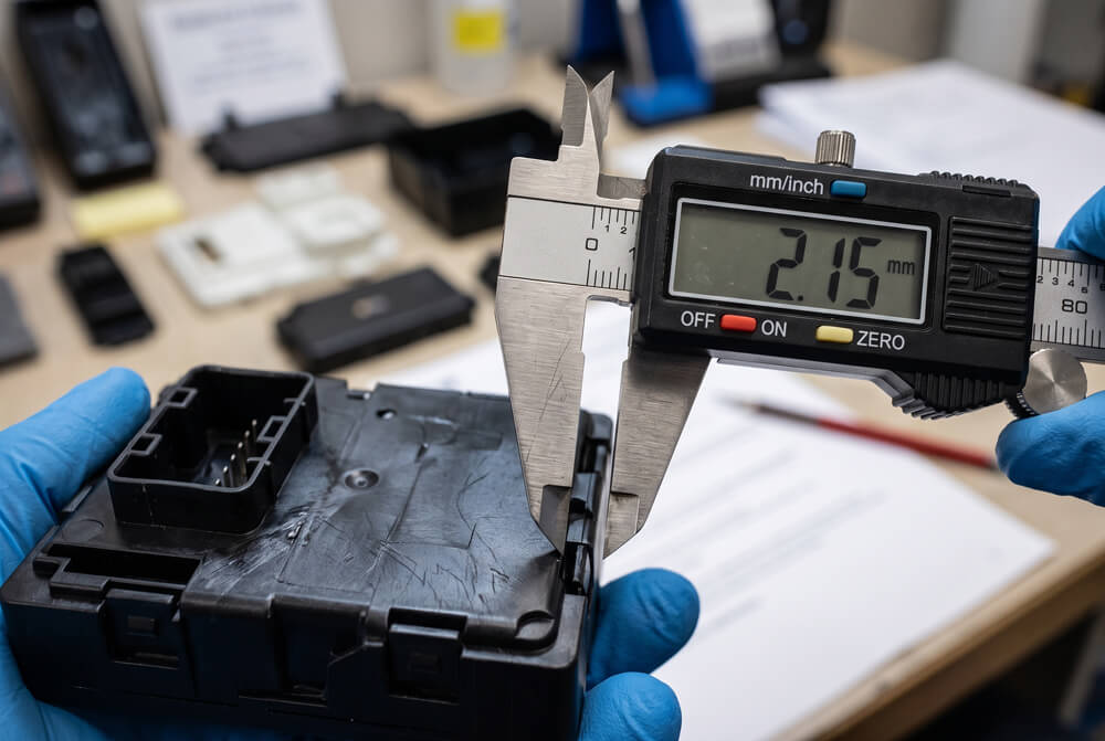 Vernier caliper measuring a finished injection molded plastic part