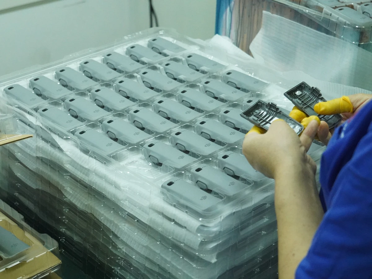 Quality inspector comparing two molded plastic parts side by side with a caliper