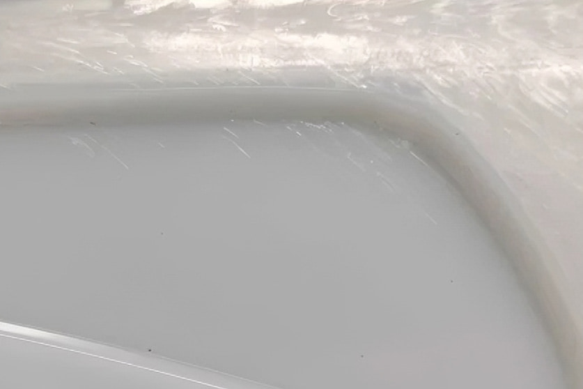 Close-up of a molded plastic part surface showing a silver streak defect near the gate