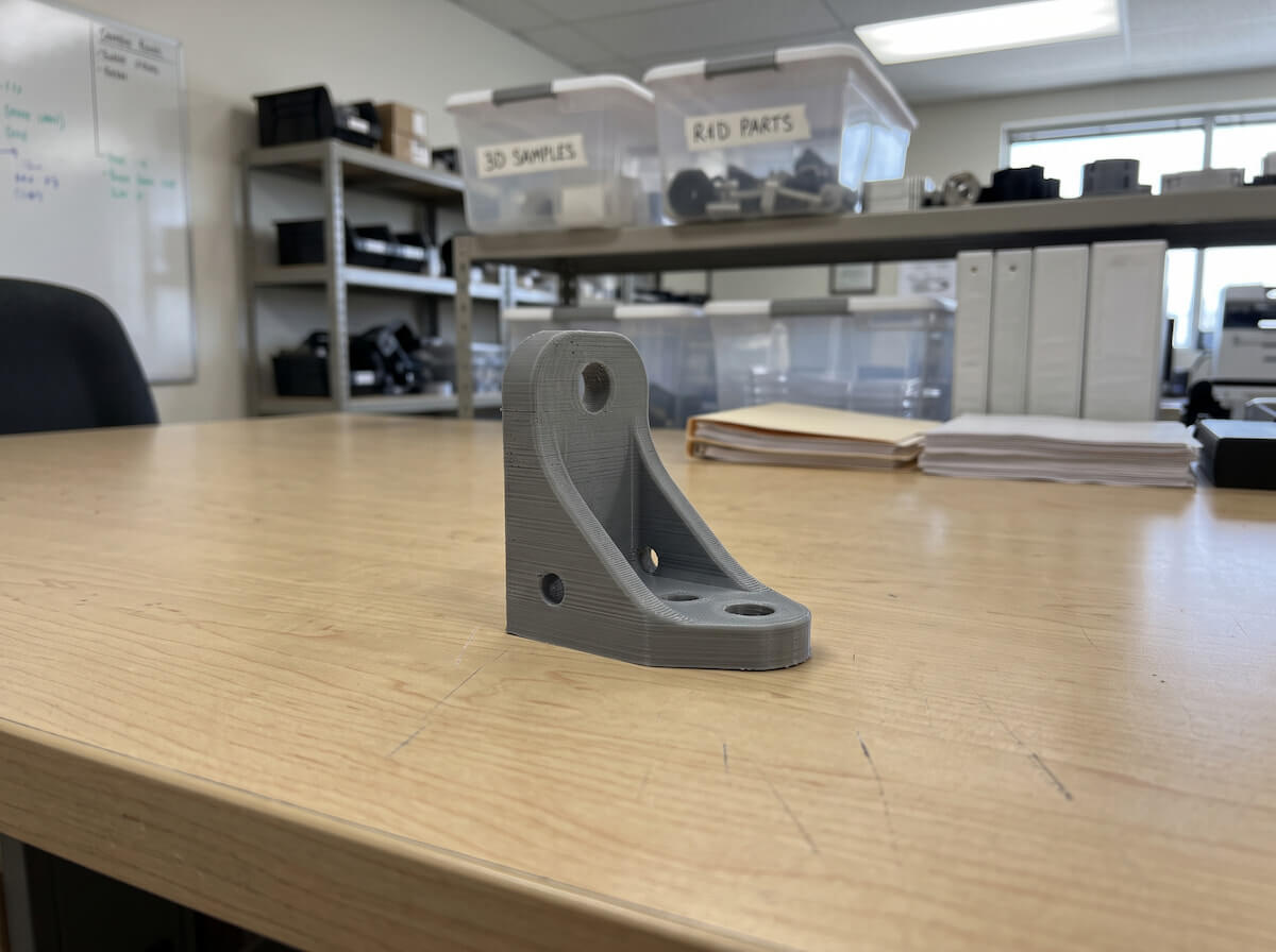 A 3D printed plastic prototype part with visible layer lines sitting on a table