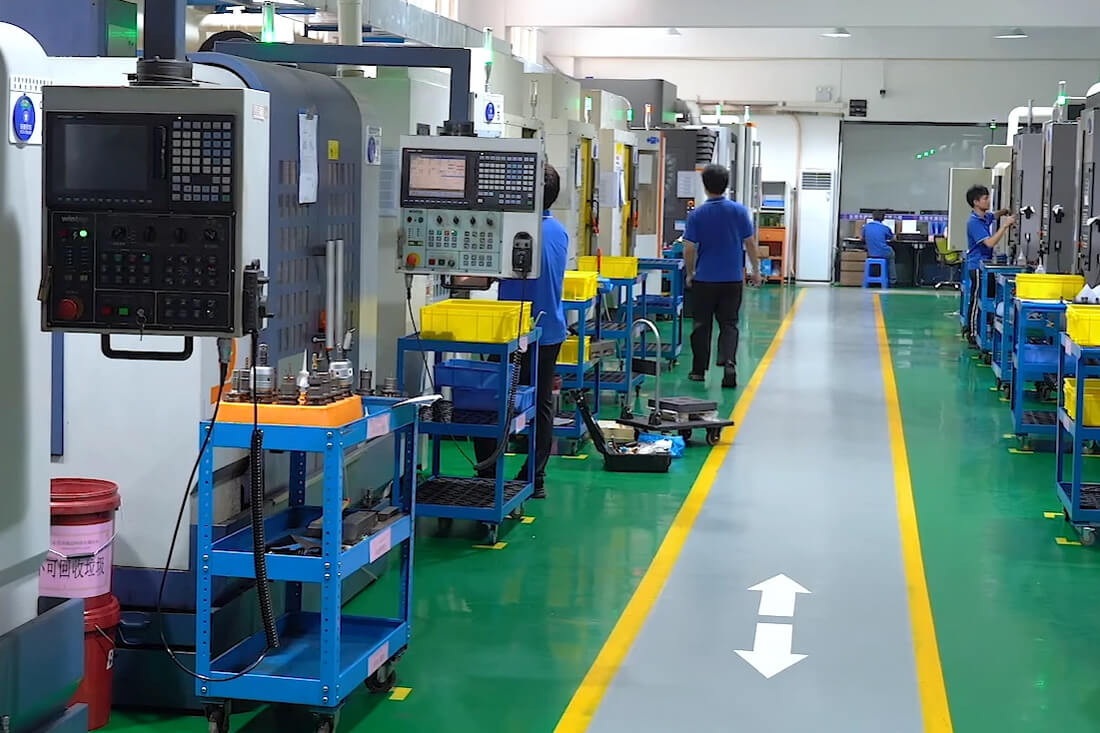 Monitor on a production floor displaying a cavity pressure curve graph next to an injection molding machine