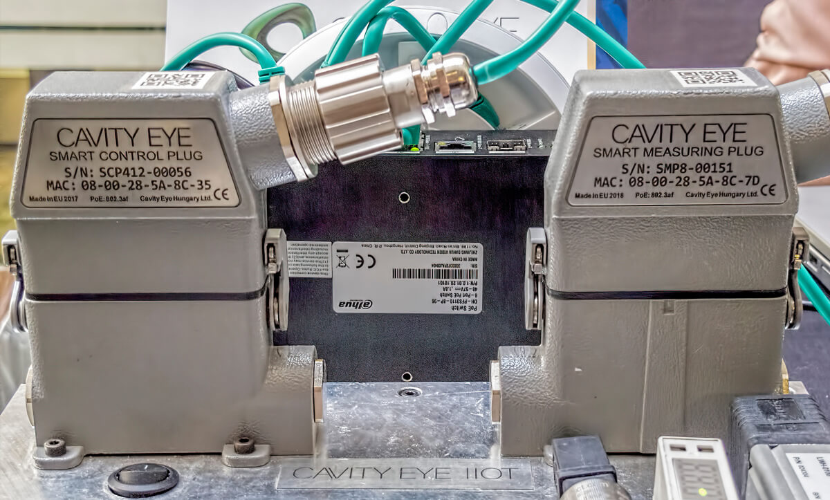 Cavity pressure sensor wiring on an injection mold next to a row of DOE trial sample parts