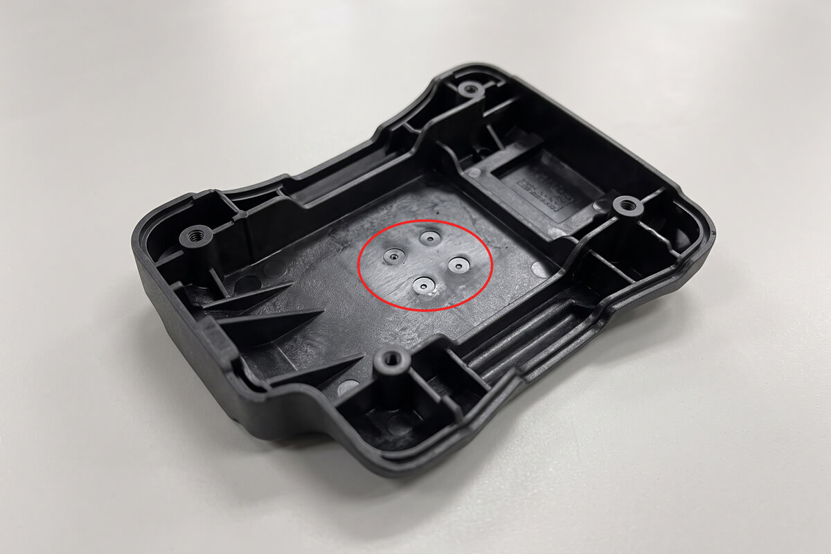 Back surface of a molded plastic part showing small circular ejector pin witness marks