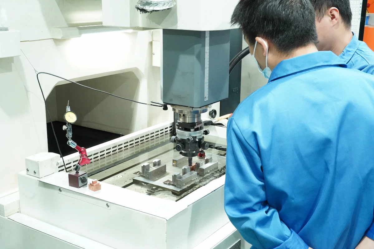 Technician adjusting injection molding machine settings during a process trial