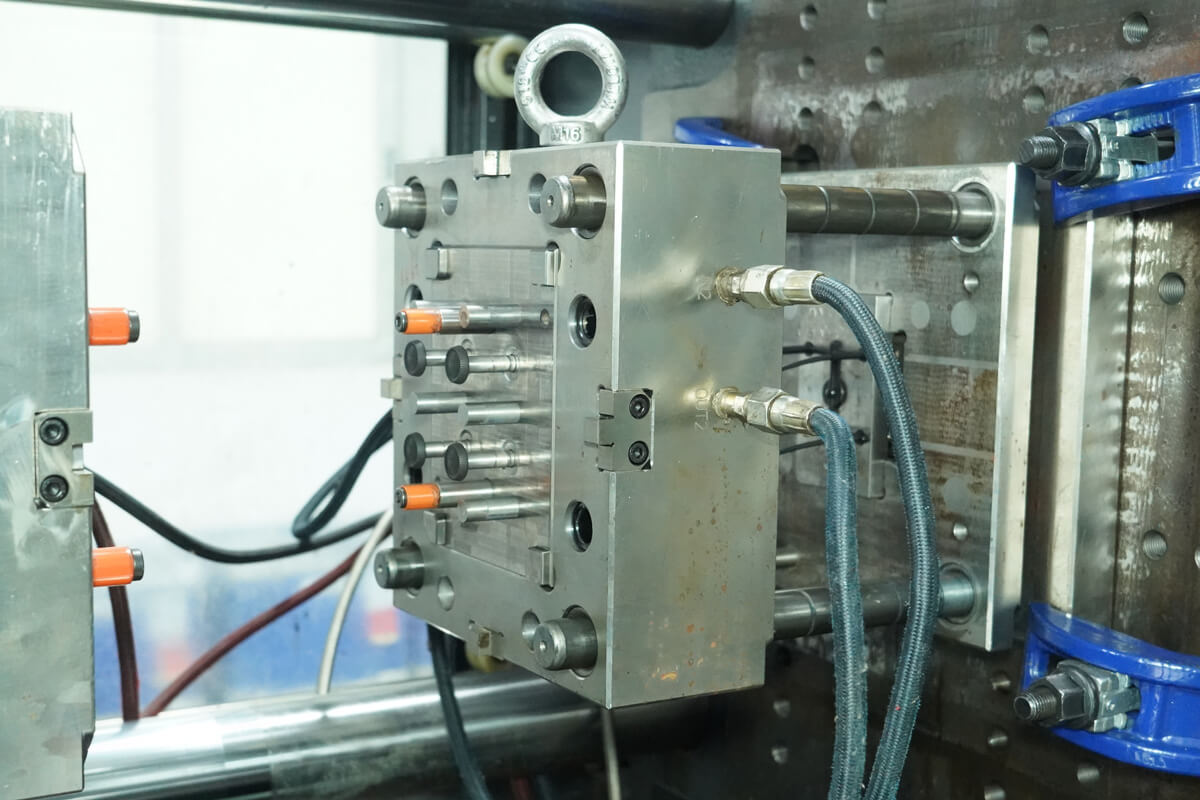 Close-up of coolant hose fittings connected to an injection mold's cooling channel ports