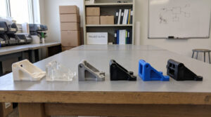 Several versions of the same small plastic part made by different prototyping methods lined up together