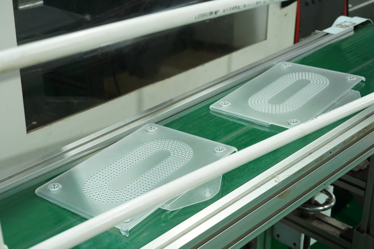 Small vision inspection camera mounted above a conveyor carrying molded plastic parts