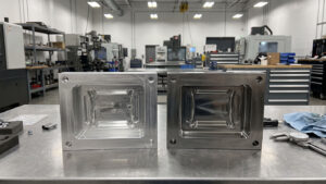Aluminum mold insert and hardened steel mold insert side by side on a workbench Figcaption: Soft tooling in aluminum (left) and hard tooling in hardened tool steel (right): same cavity concept, different service life.