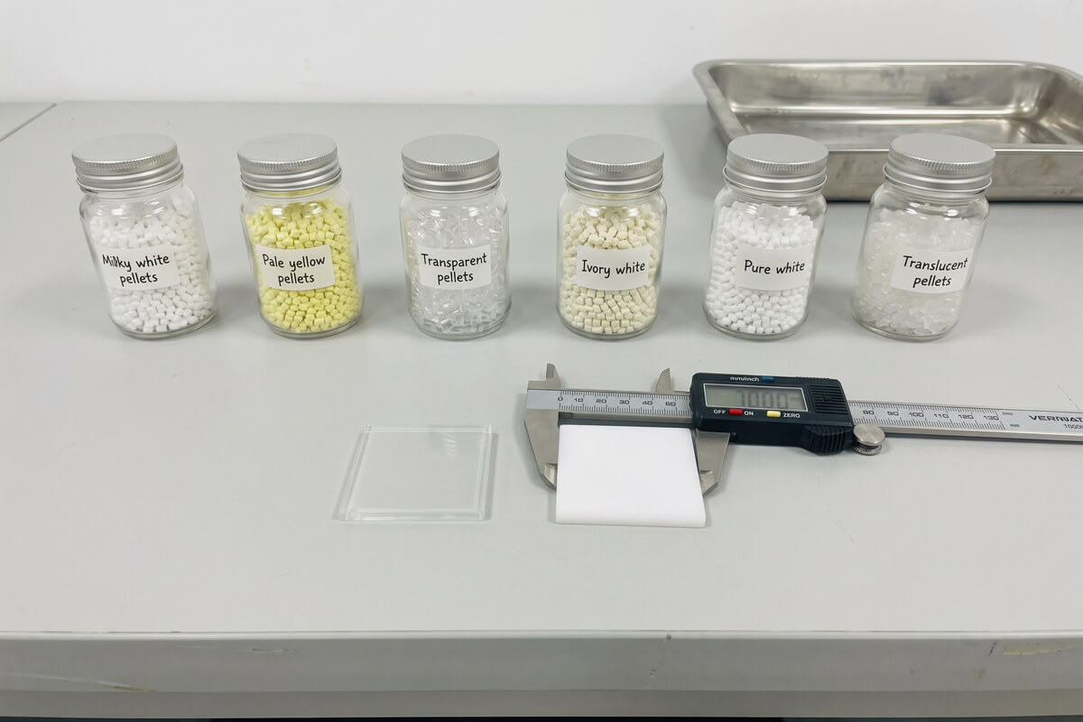 A clear molded plaque and an opaque white molded plaque with a digital caliper measuring the white plaque