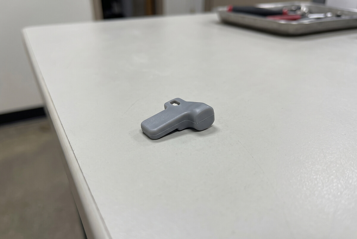 Clean, flash-free injection molded plastic part next to inspection tools on a table