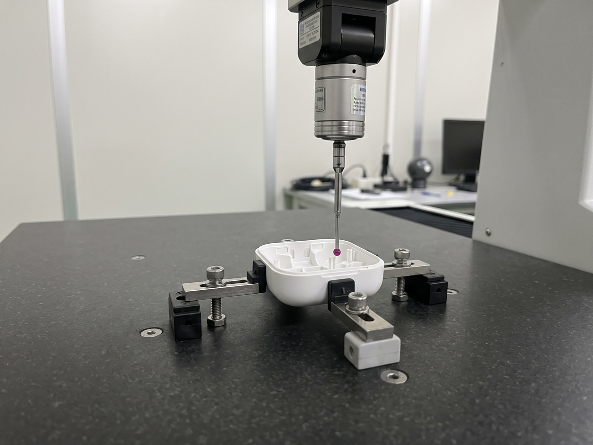 Coordinate Measuring Machine CMM probe inspecting the internal mounting bosses of an injection-molded smart device enclosure
