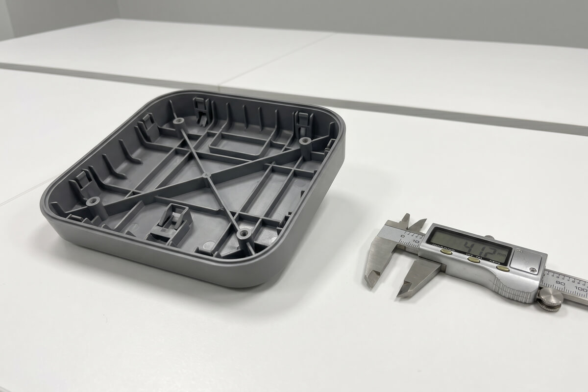 Inside view of an injection-molded plastic enclosure showing uniform cored-out wall thickness and reinforcing ribs on a white inspection table