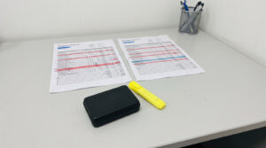 Two printed injection molding quotations side by side on a desk with a black molded sample part and a highlighter