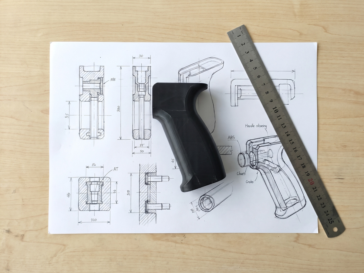 Hand-drawn industrial design concept sketch next to a CNC-machined ABS functional prototype on a studio worktable