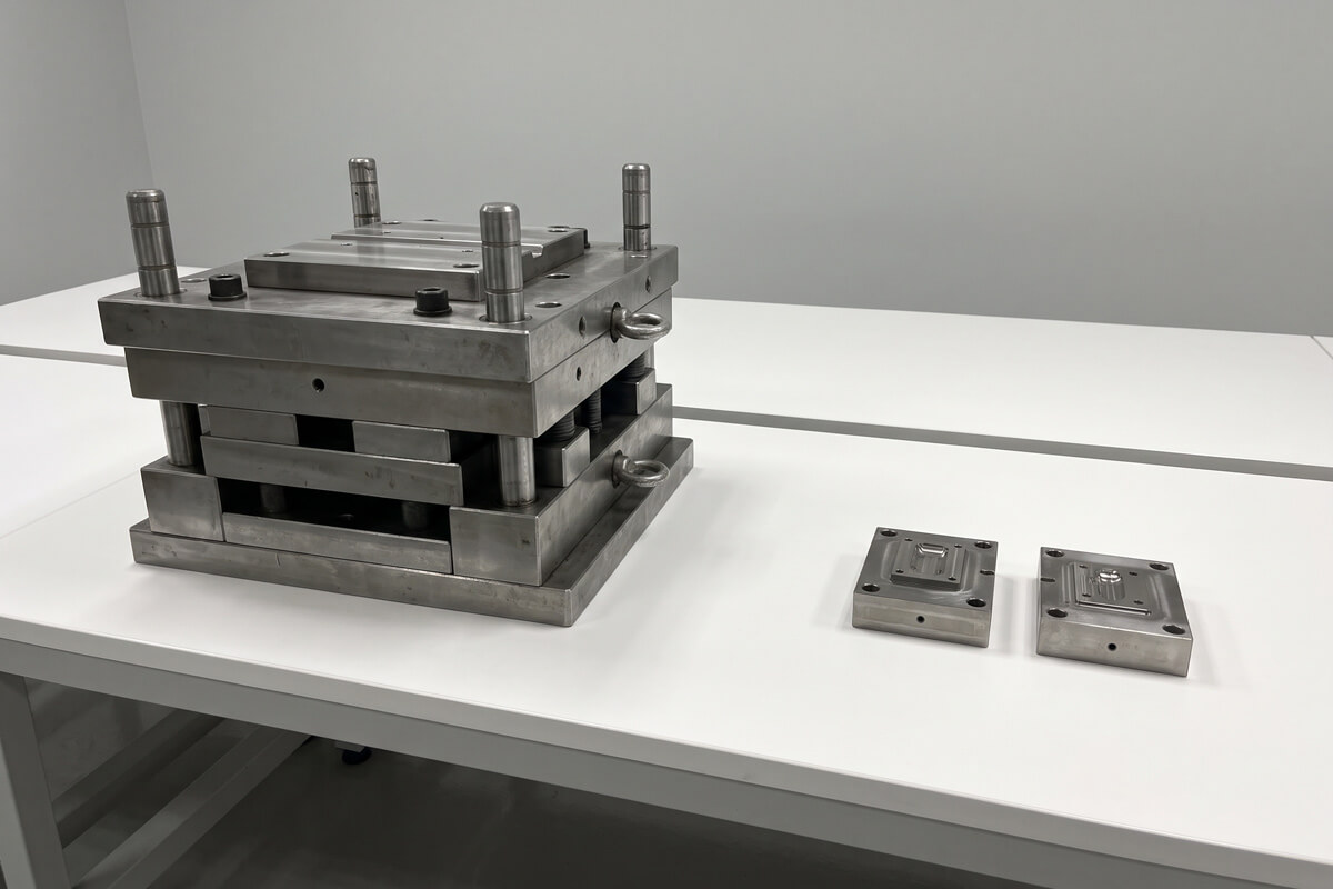 Comparison between a heavy standalone steel mold base and a compact MUD rapid tooling core and cavity insert on a worktable