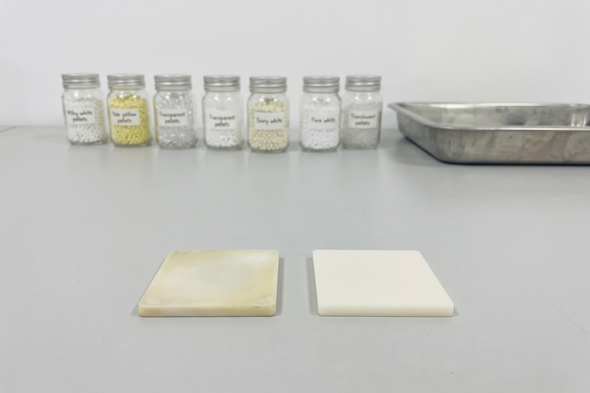 Two molded plastic plaques side by side, one yellowed from UV aging and one new, on a lab bench