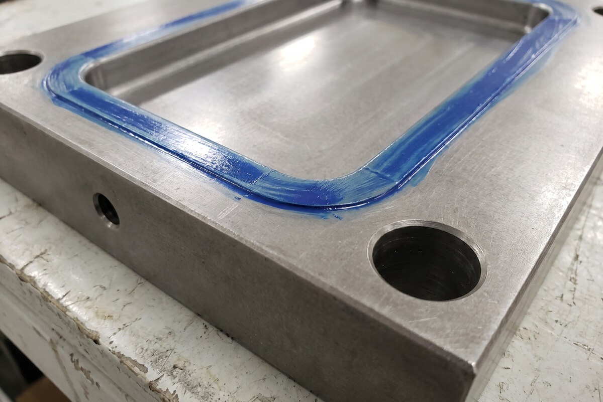 Close-up of an injection mold cavity parting surface with blue marking showing contact across the shut-off band