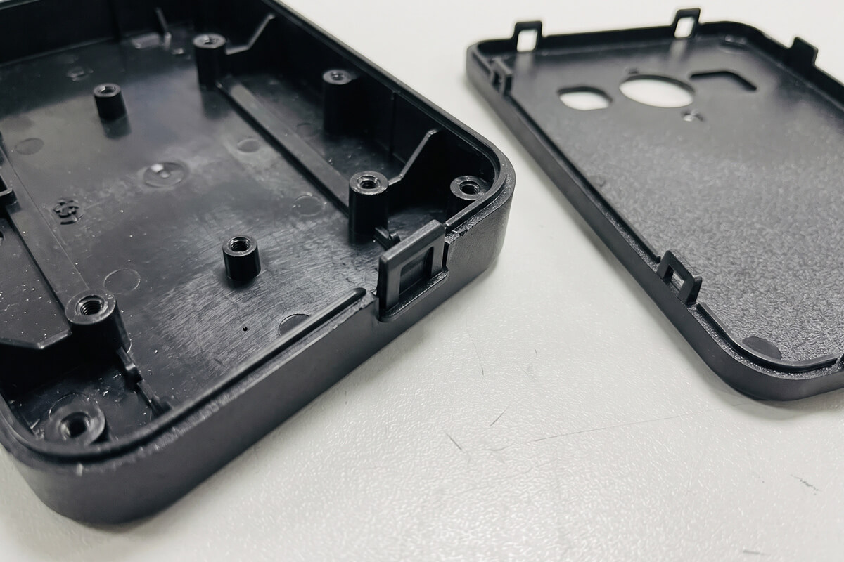 Close-up of a molded enclosure lid and base showing the snap-fit lip, a critical injection molding tolerance feature