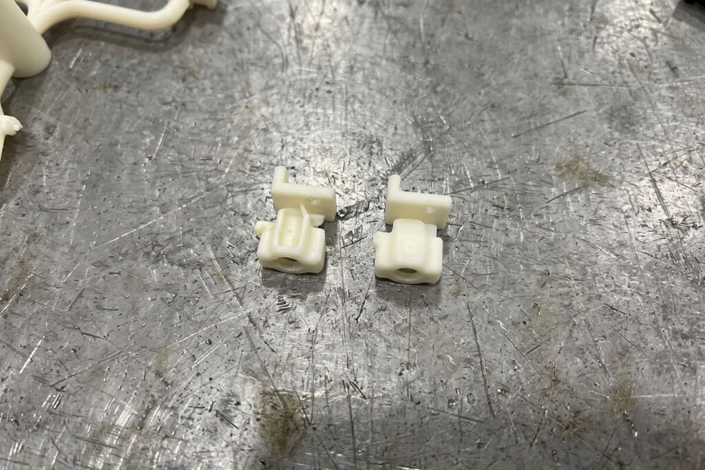 Close-up of two molded parts showing a raised hot tip gate vestige and a nearly flush valve gate mark