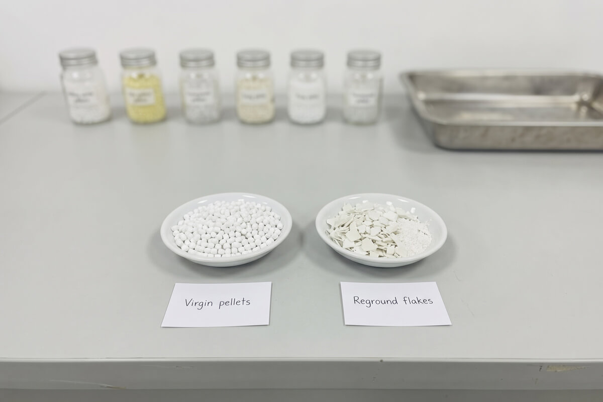 Two white dishes, one with smooth virgin resin pellets and one with irregular ground regrind flakes