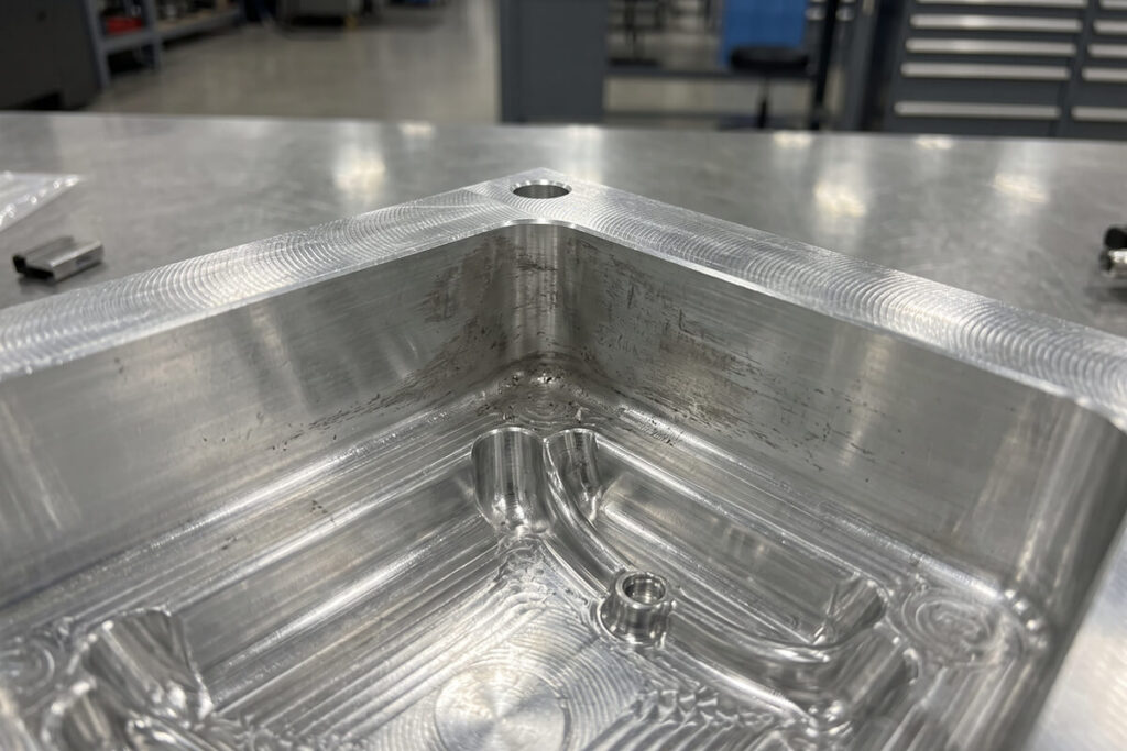 Close-up of an aluminum mold cavity with dull worn spots around the gate area